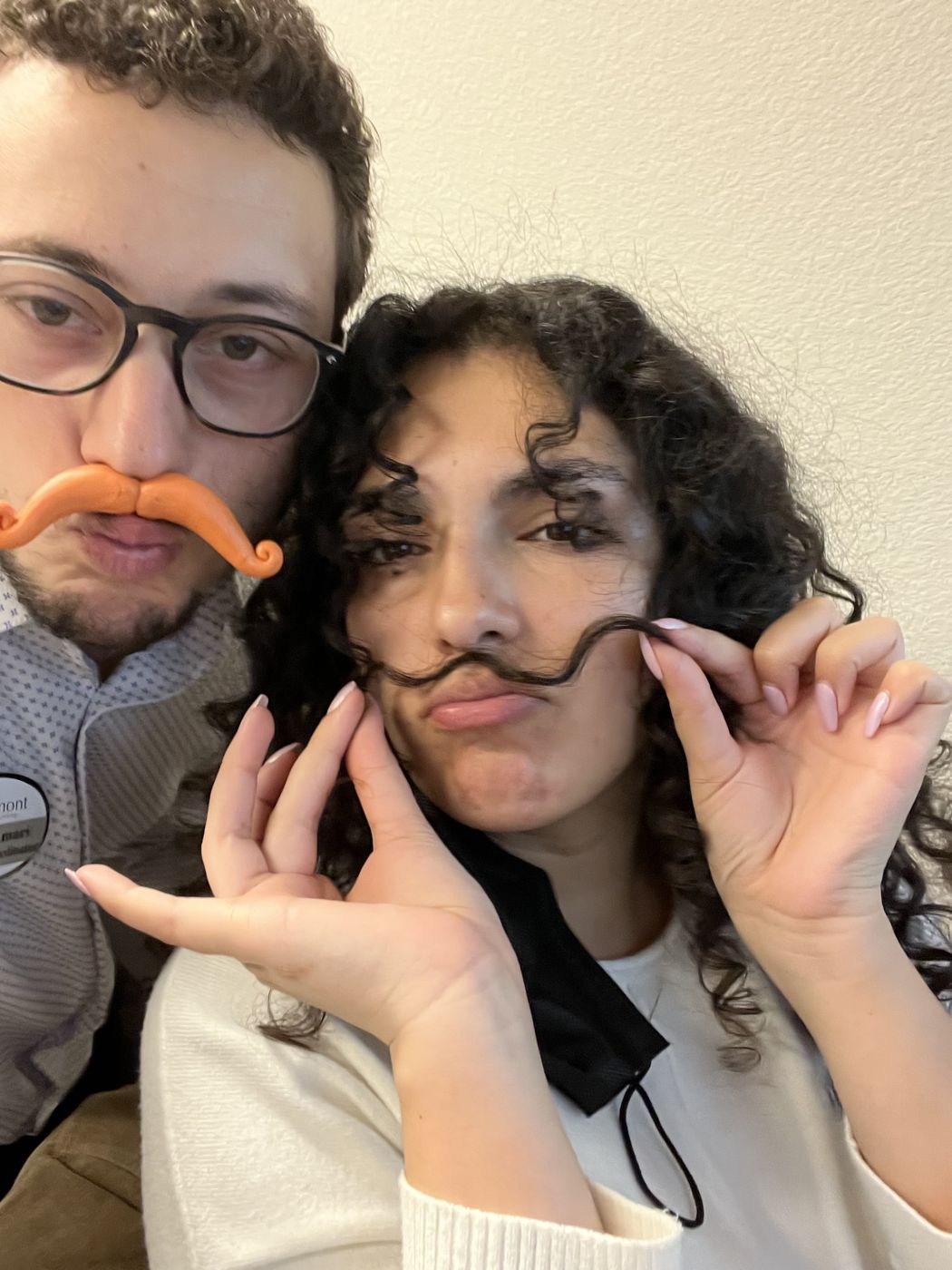 Tristan and Ileana goofing around with mustaches, his fake and hers made from a curl of her hair