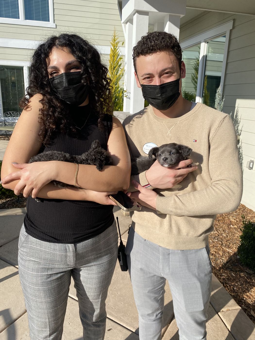 Ileana and Tristan in masks at Oakmont, each holding a puppy