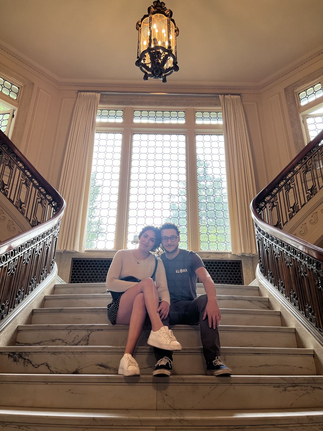 Tristan and Ileana sitting on a grand staircase